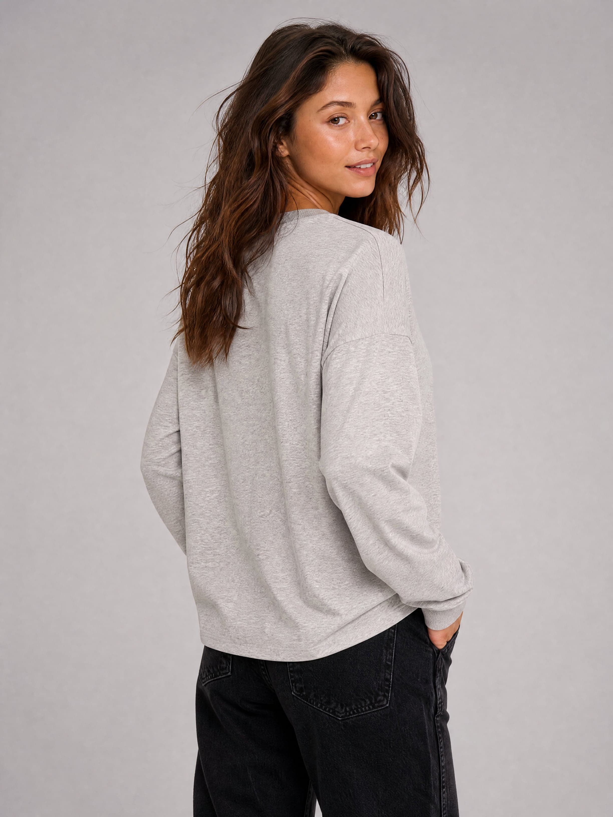 Szara bluzka longsleeve z długim rękawem, widok od tyłu, na modelce.